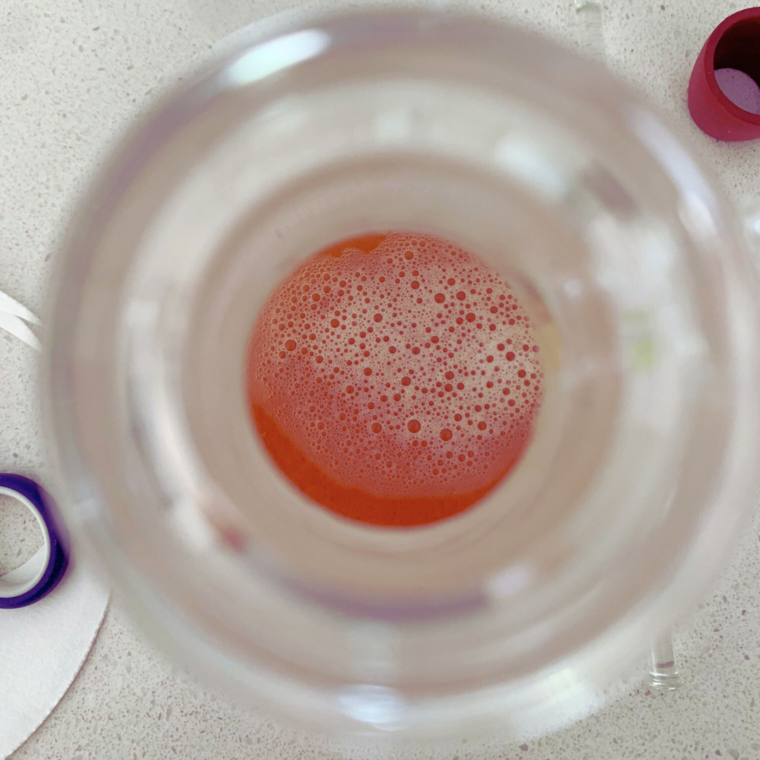 Zoom in into a beaker with a bright red herbal extract